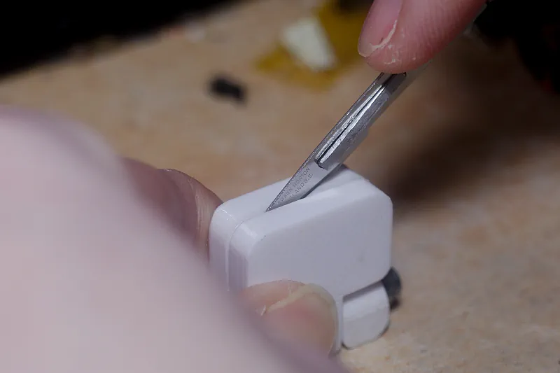 Een wit hulpstukje van ongeveer 2 centimeter groot en 2 centimeter hoog om een VT506 microfoontje veiliger open te snijden