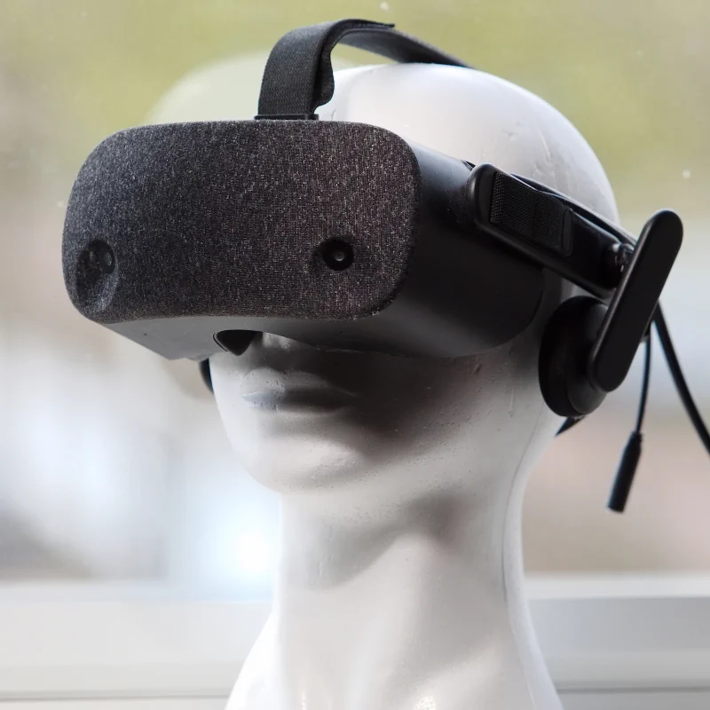 Een in daglicht gefotografeerde Virtual Reality Headset van Hewlett Packard.  Het toestel is zwart-grijs en bevat een textielen front waarin de twee camera's te zien zijn.  De headset is geplaatst op een wit piepschuimen hoofd van een mannequin, voor een groot raam.