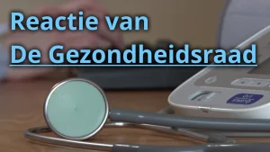 Een stethoscoop (een medisch hulpmiddel) ligt naast een bloeddrukmeter op het bureau van een arts, terwijl onscherp in de achtergrond de dokter een toetsenbord bedient.